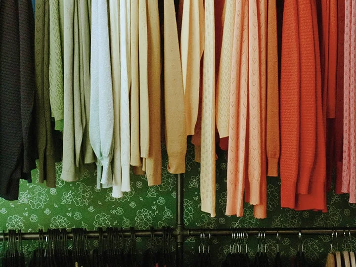 Farbenfrohe Kleider und Strickjacken auf Kleiderständern